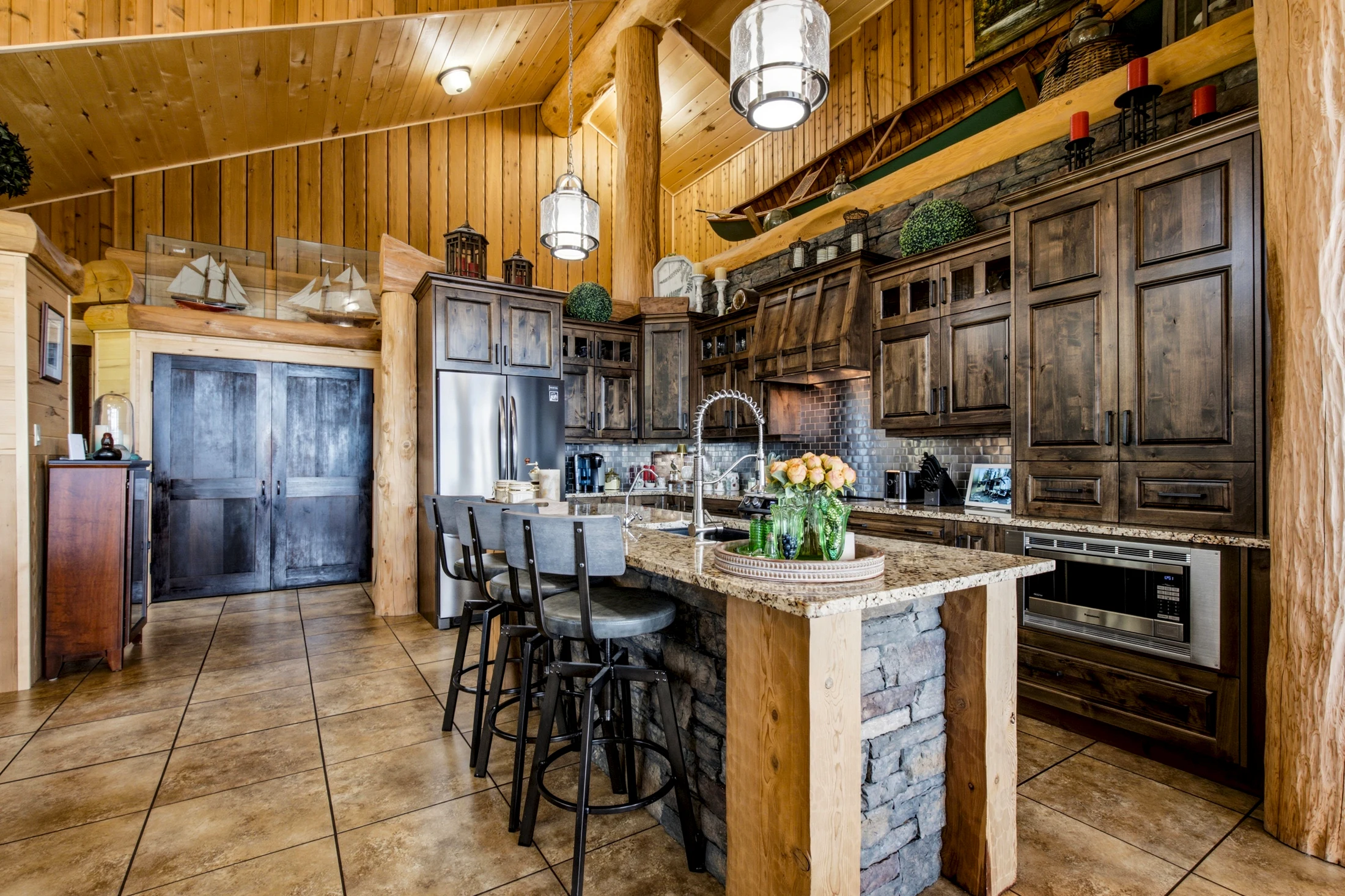 Gourmet kitchen with dark cabinetry, stone counters and substantial cedar beams